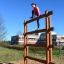 Femme grimpant sur Step And Climb wooden ladder dans une aire de jeux extérieure.