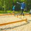 Personnes en équilibre sur des poutres en bois dans une salle de sport extérieure utilisant le produit Balance.