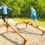 Deux personnes en équilibre sur l’équipement de fitness extérieur Easy Balancer dans un parc.