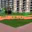 Installation d'équipements de terrain de jeu verts sur une surface orange devant des immeubles d'habitation.