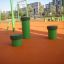 Piquets de saut verts (5 pièces) sur une aire de jeux extérieure avec revêtement en caoutchouc orange.