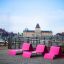 Lounge chair rose installé sur une terrasse en bois avec vue sur la ville en arrière-plan.