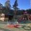 Twister castle with slide dans une aire de jeux avec des arbres autour et un abri