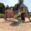 Twister castle with slide sur une aire de jeux sablonneuse.