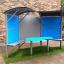 Shelter with table pour des sièges extérieurs avec panneaux bleus.