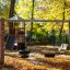 Nature Swing Frame (double swing) dans un parc en automne avec des balançoires à pneus et une structure de jeu au fond