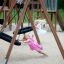 Deux filles jouant sur Double Swing (BNS 90cm) dans l'aire de jeux.
