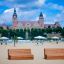 Bancs en bois Sofa Wave sur une plage de sable avec un château en arrière-plan.