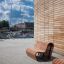 Bancs extérieurs en bois Sofa Wave près d'un bâtiment moderne aux murs en briques.