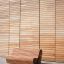 Banc extérieur moderne en bois devant un mur en bois.