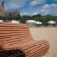 Mobilier extérieur Sofa Wave sur une plage de sable avec des parasols et des bâtiments en arrière-plan.