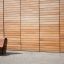 Mobilier moderne en bois Sofa Wave devant un mur en bois.