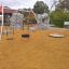 Double Swing équipement de jeu avec deux balançoires, dont une balançoire en pneu, dans une aire de jeu sablonneuse.