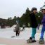 Enfants s’amusant à faire du skateboard dans un skatepark extérieur avec des rampes.