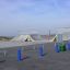 Rampes et rails de skatepark avec bornes bleues et poubelles vertes.