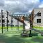Équipement de aire de jeux New Age Fit MEDIUM avec mur d’escalade et toboggan en extérieur.