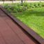 Rubber Tiles 55 revêtement de sécurité pour aire de jeux en rouge foncé à côté de l'herbe verte et des plantes