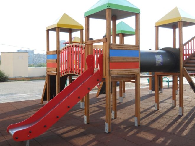 Aire de jeux avec toboggan rouge et structures en bois sur Rubber Tiles 55.
