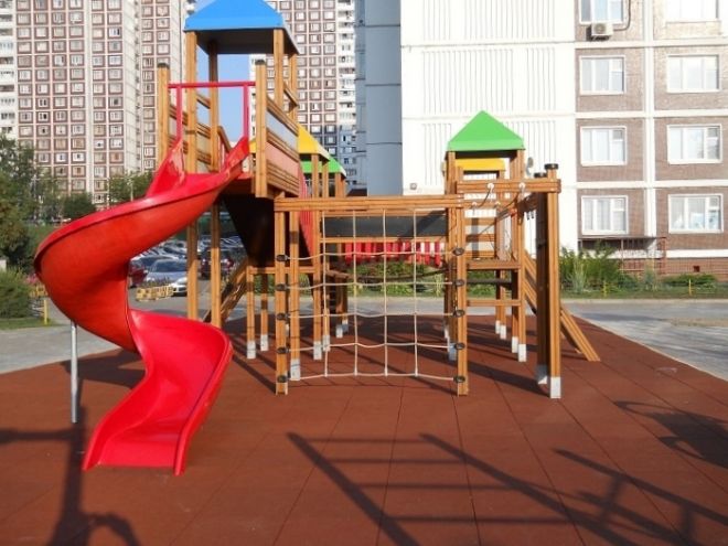 Aire de jeux pour enfants avec structures en bois et toboggan rouge sur Rubber Tiles 75.