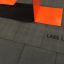 Revêtement noir Rubber Tiles 75, logo Lars Laj, sous une structure orange.