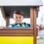 Enfant jouant à l'intérieur du Villa Maxi sandbox with a playhouse.