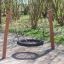 Balançoire de terrain de jeu BNS Single Swing Robinia 2 Posts en bois avec siège en pneu noir dans un parc.