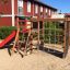 Terrain de jeu Climbing Kiosk (Wide Slide) dans une aire de jeu sablée avec une structure en bois, escalade à corde n