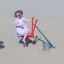 Enfant jouant sur un équipement de jeu rouge Excavator dans un bac à sable