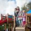 Des enfants jouent sur une grande structure de jeu en bois avec un toboggan.