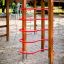 Activity Center with Slide en bois avec des barres d’escalade rouges dans une aire de jeux sablée.
