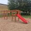 Activity Center with Slide sur une aire de jeux sablonneuse avec des éléments d'escalade et un toboggan rouge