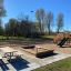 Aire de jeux en bois avec balançoires, toboggan et bac à sable dans un parc.