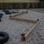 Parcours Balance composé de poutres en bois et de pneus dans une aire de jeux.