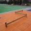 Équipement de jeu à poutres Balance sur un tapis orange avec un champ vert en arrière-plan.