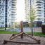 Structure d’escalade en bois Atakama sur une aire de jeux devant de hauts immeubles résidentiels.