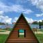 Structure de terrain de jeu en bois Small House Grass Roof avec toit vert dans un parc.