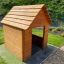 Nature Playhouse en planches de bois dans une cour arrière herbeuse.