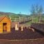 Nature Playhouse dans un cadre extérieur naturel avec des structures de jeu en bois et une clôture en osier.