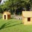 Deux structures en bois Nature Playhouse sur l’herbe avec des arbres en arrière-plan.