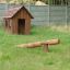 Nature Playhouse dans une cour arrière herbeuse avec une balançoire en bois.