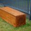 Cube banc en bois pour aire de jeux sur l'herbe verte près d'une clôture métallique