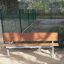 HPL Bench dans un parc avec des pieds en métal et une assise et un dossier en bois.