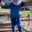 Un enfant traverse l’équipement de jeu Chain Bridge avec l’aide d’un adulte.