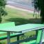 Table HPL vert avec des bancs verts dans un cadre de parc.