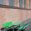 Table & Bench HPL vert installé contre un mur de briques à l'extérieur.