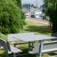Table & Bench Quadro HPL d'extérieur installé dans un paysage de parc verdoyant.