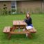 Larchwood Table & Bench for Kids avec une fille assise sur le banc dans un cadre de jardin