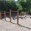 Terrain de jeu extérieur avec équipement d'escalade en bois Somersault Triple et barres rouges.