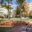 Équipement de fitness extérieur dans un parc avec des arbres et des immeubles d’habitation en arrière-plan.