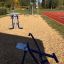 Équipement de gym extérieur 'Double Ski Trainer' dans un parc près d’une piste de course.